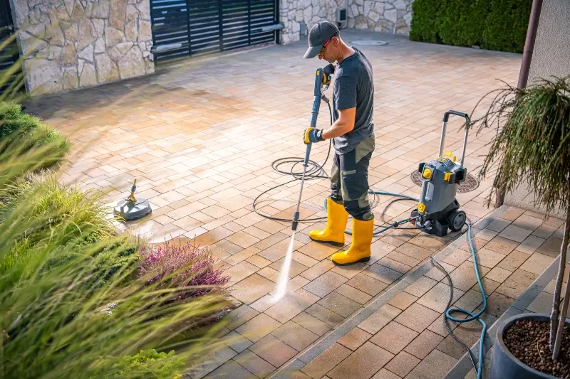 A wide shot of a worker pressure washing the courtyard of an apartment building