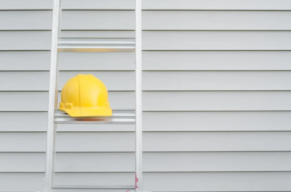 new gray siding on a Pacific Northwest house, with a ladder and hardhat in front
