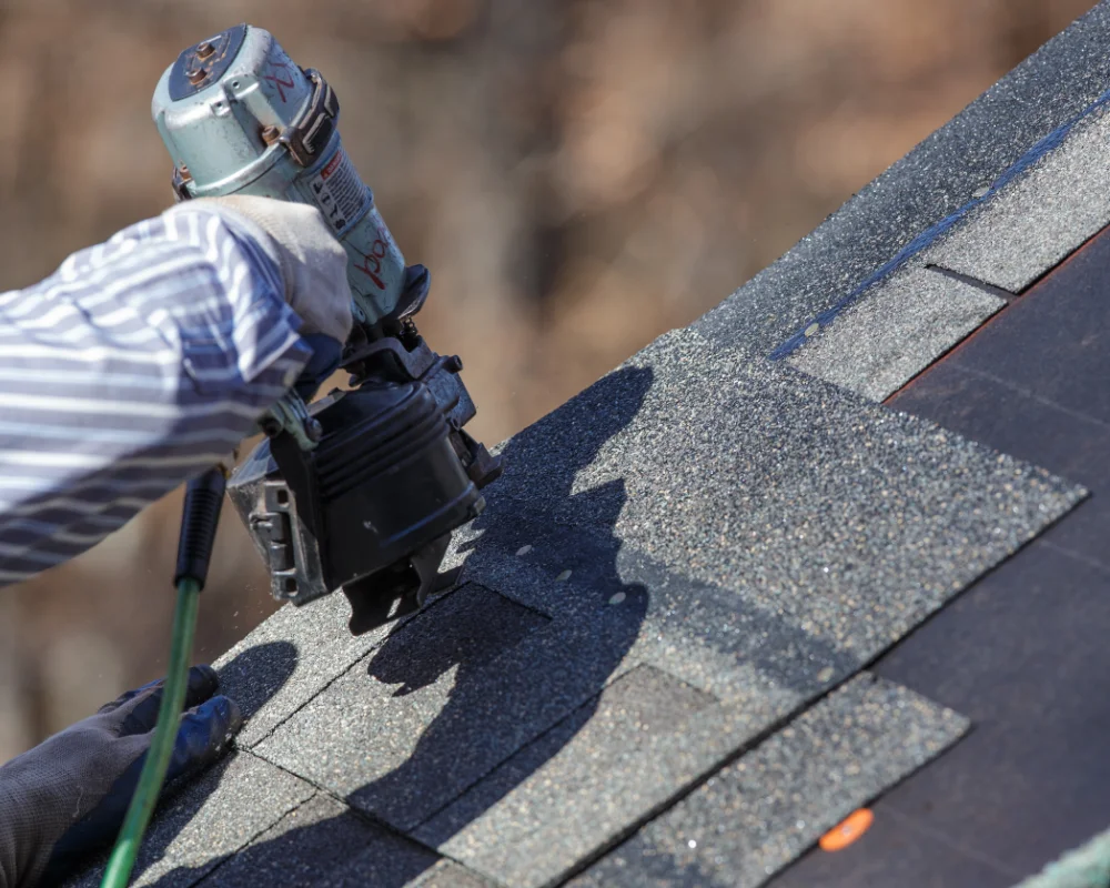 Closeup shot of a nailgun being used to install new roofing tiles.